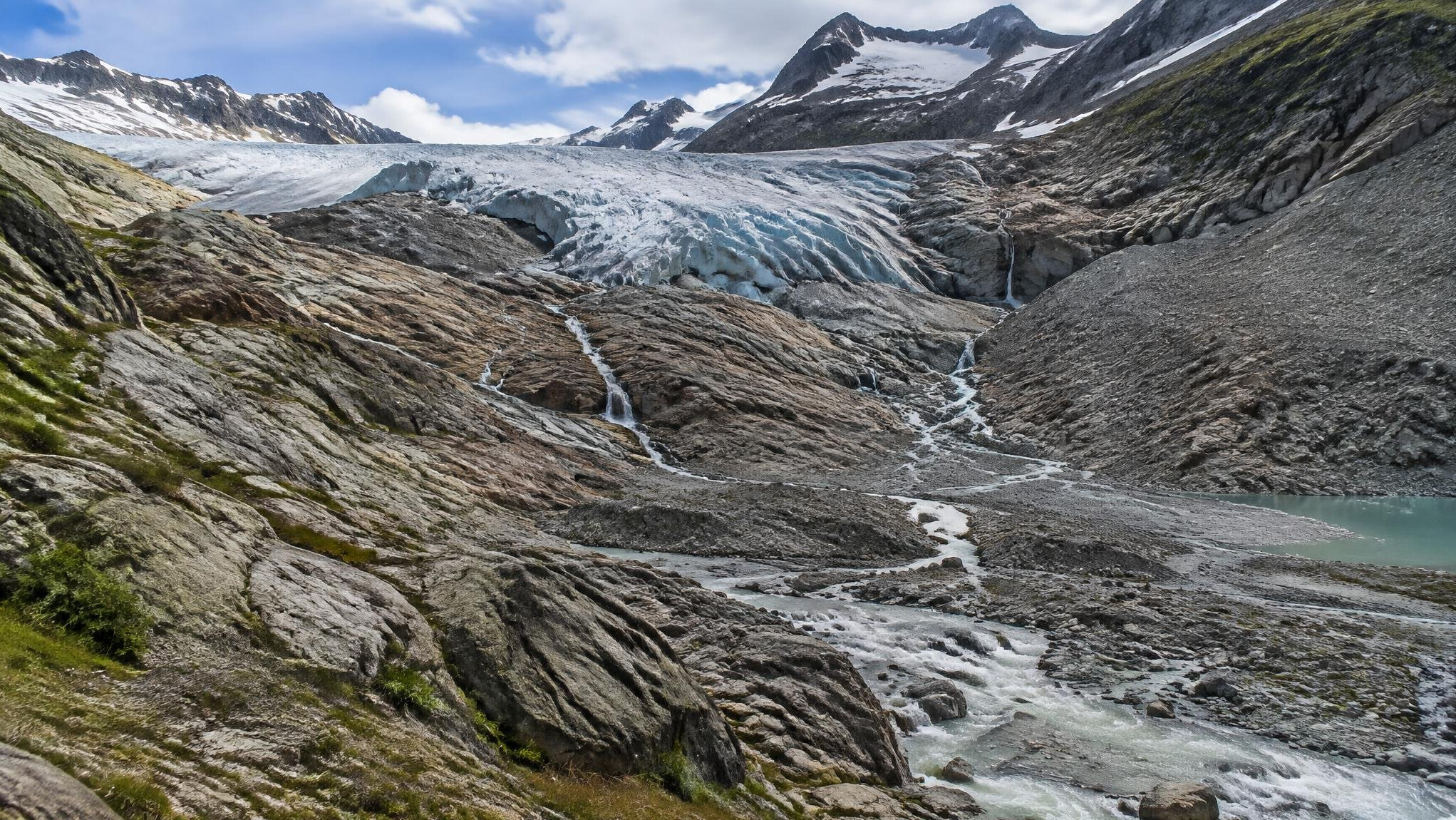 Retreating alpine glacier showing exposed rock and meltwater streams