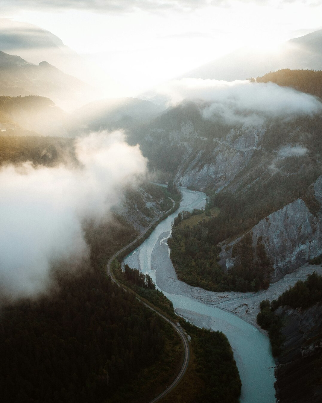 Aerial view of a Swiss river valley with industrial facilities in the distance